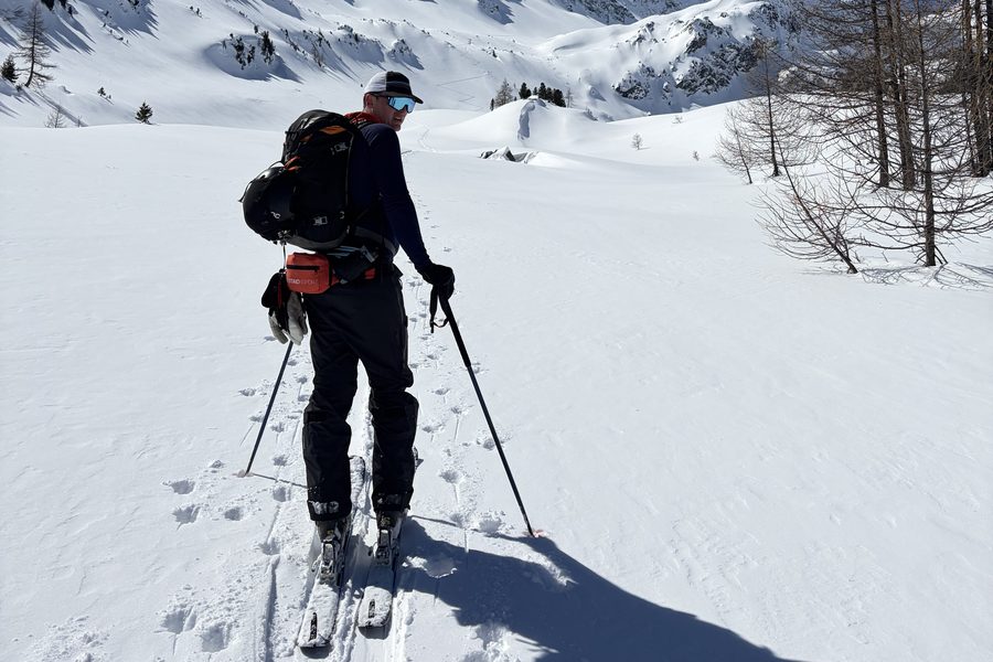 Connor Maxwell ski touring in the Alps, with snow-covered peaks behind